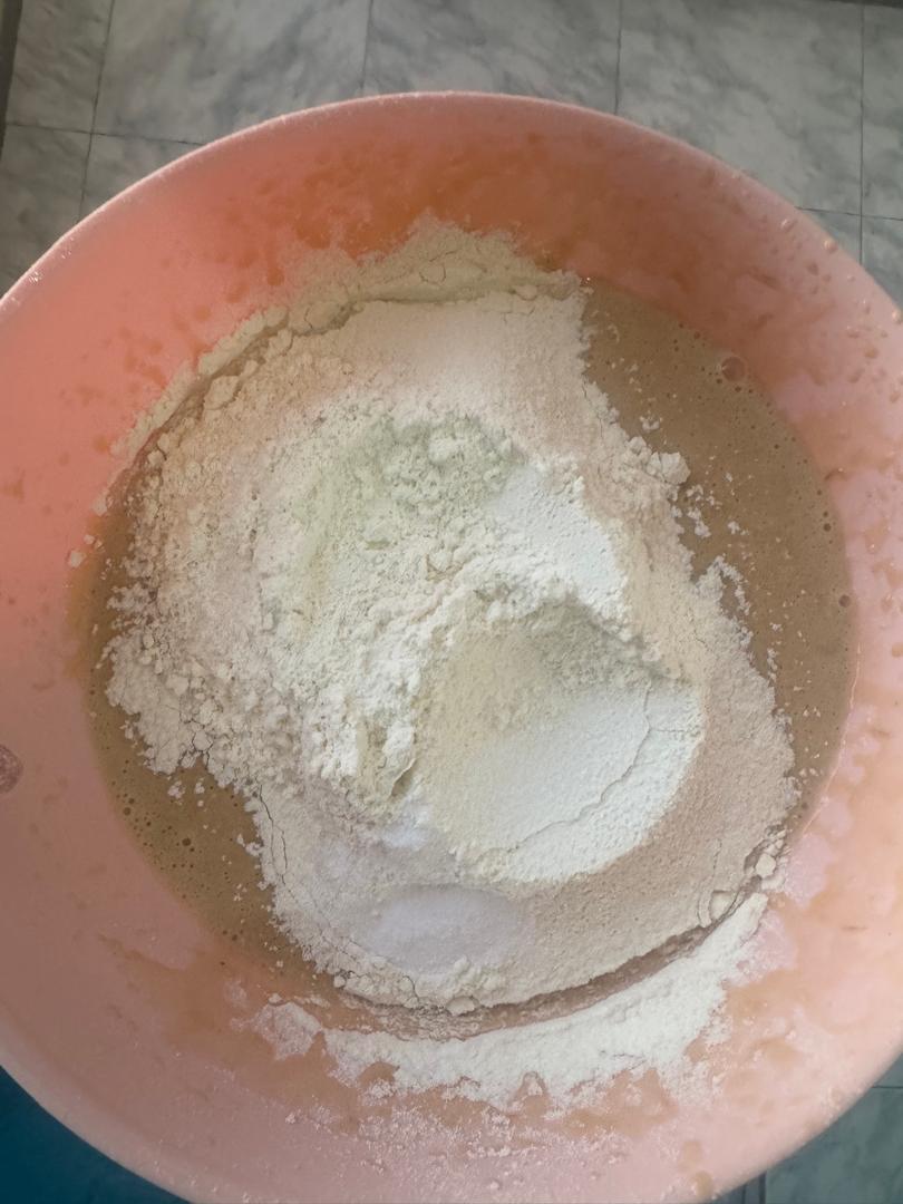 Dry flour added to the wet mixture in a pink bowl