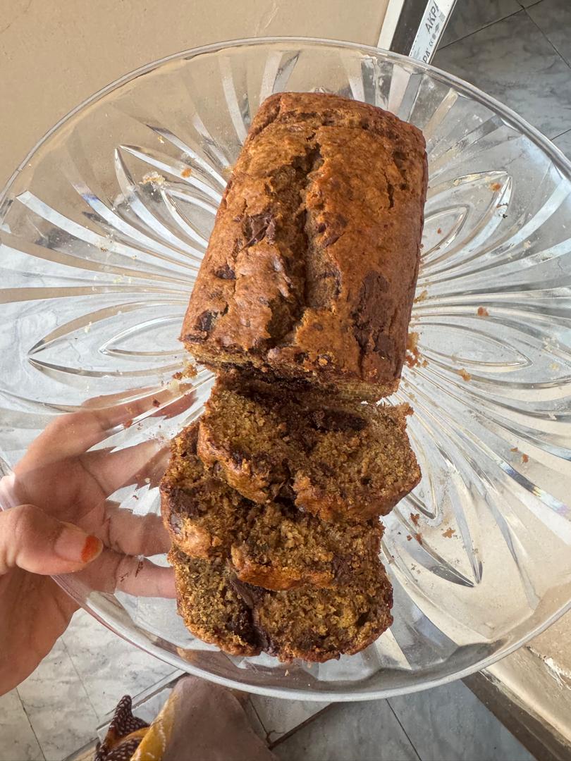 Sliced date syrup banana bread with chocolate chunks on a glass plate