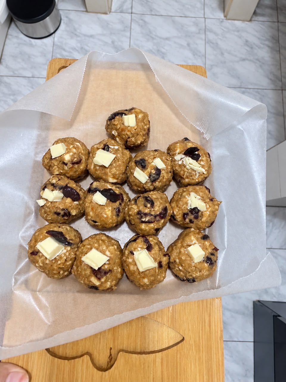 50 g cookie dough balls topped with white chocolate on parchment paper