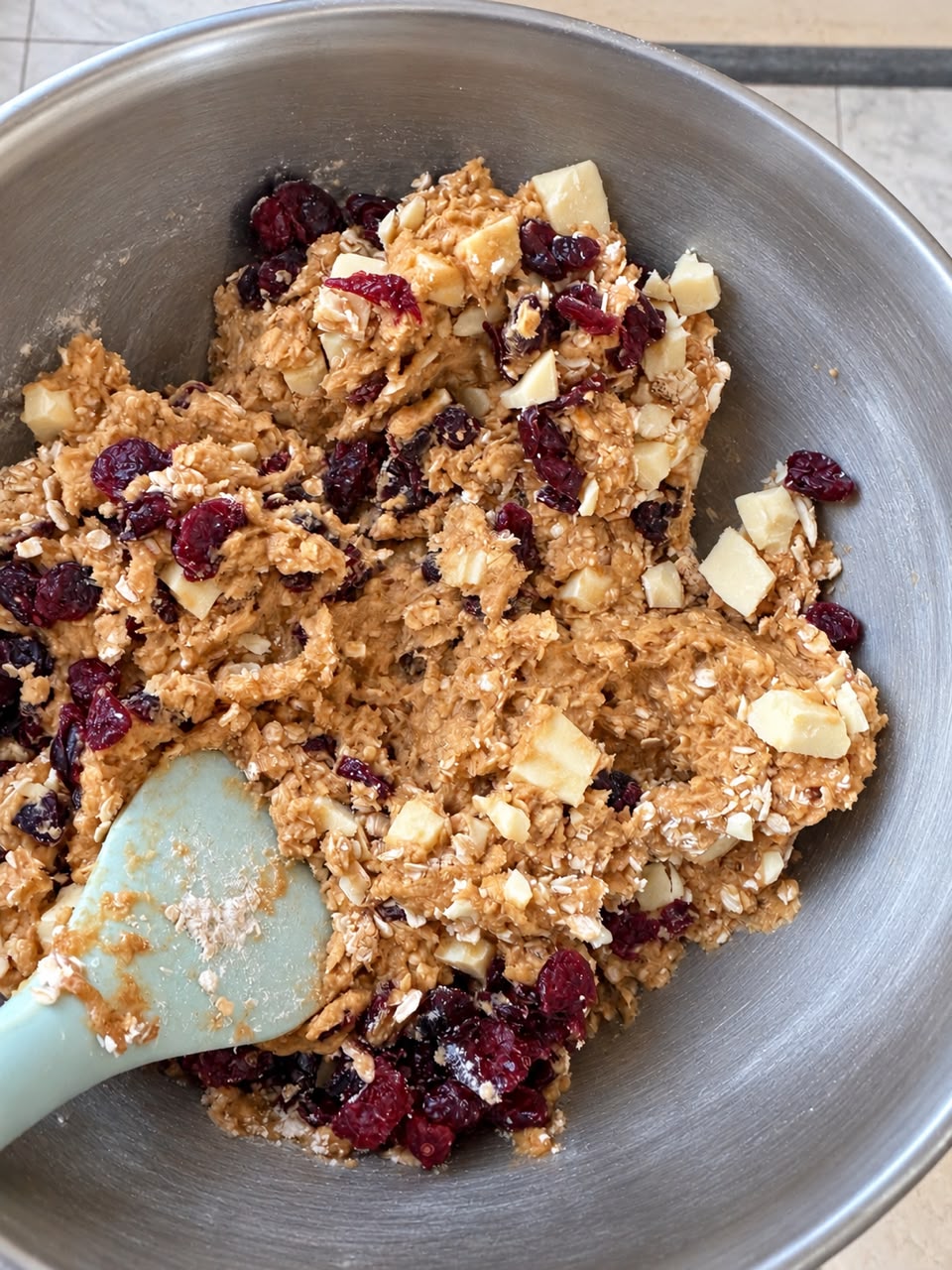 Cookie dough with oats, dried cranberries, and white chocolate chunks in a bowl